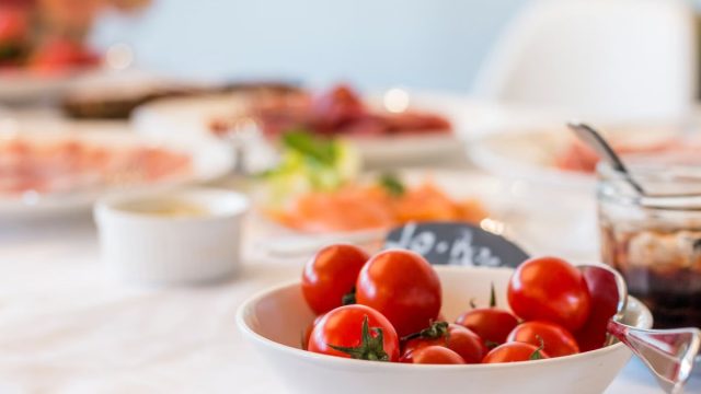Close-up shot of vibrant cherry tomatoes in a bowl on a well-set dining table.
