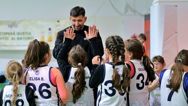 A coach giving high fives to a group of young basketball players